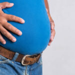 homme-adulte-de-poids-excessif-ou-gros-dans-des-jeans-très-serrés-sur-un-fond-gris-soins-de
