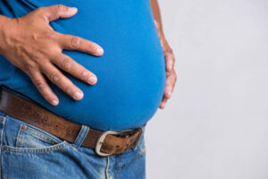 homme-adulte-de-poids-excessif-ou-gros-dans-des-jeans-très-serrés-sur-un-fond-gris-soins-de
